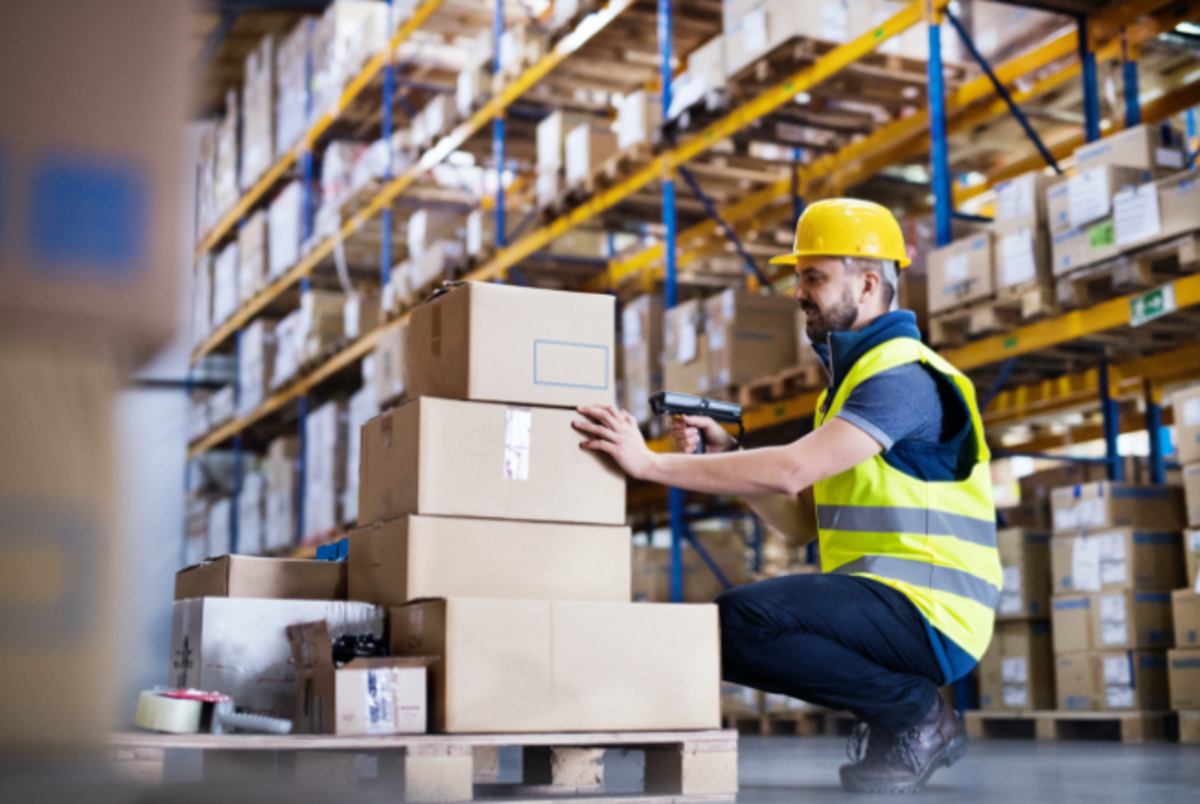 Warehouse worker dressed in hi vis clothing packing office supplies